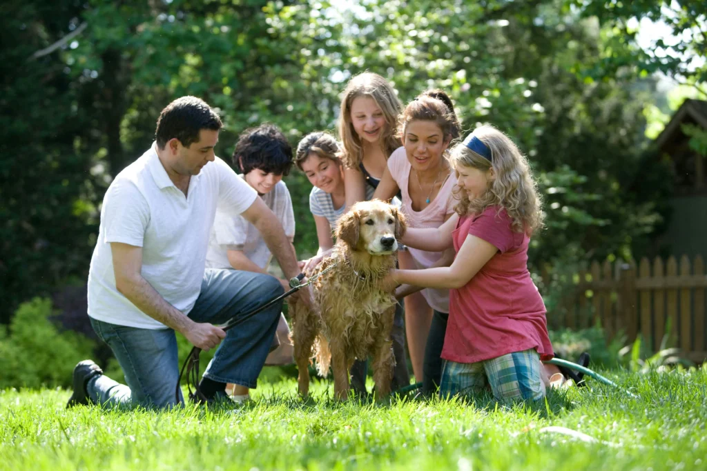 Happy family posing together with their dog in a backyard garden.