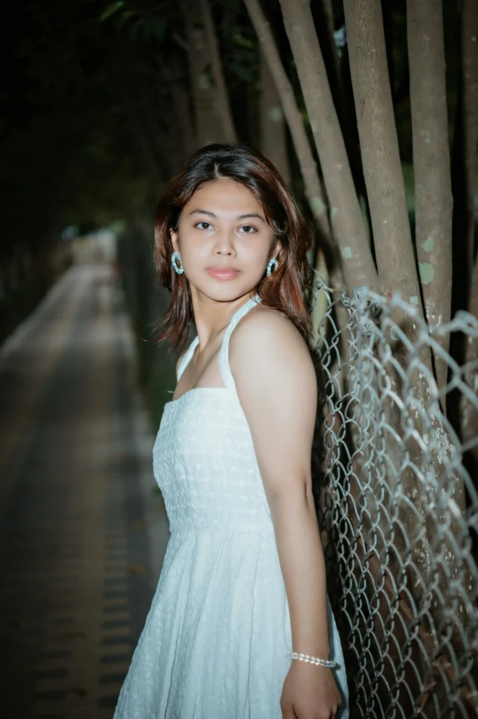 A woman wearing a white outfit posing outdoors during a photo session.