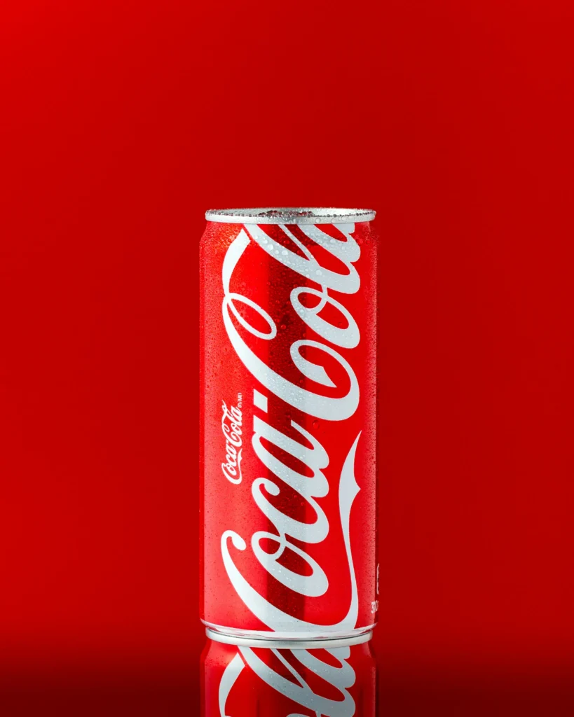 A chilled Coca-Cola bottle on a vibrant red background designed for commercial advertising.