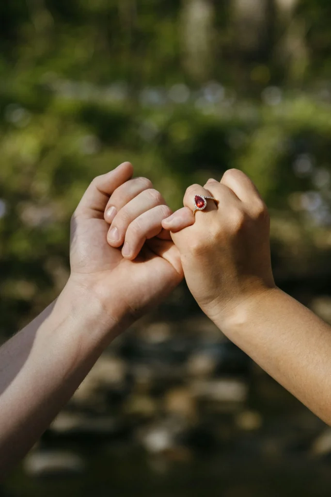 Two hands gently holding together with an engagement ring in sharp focus.