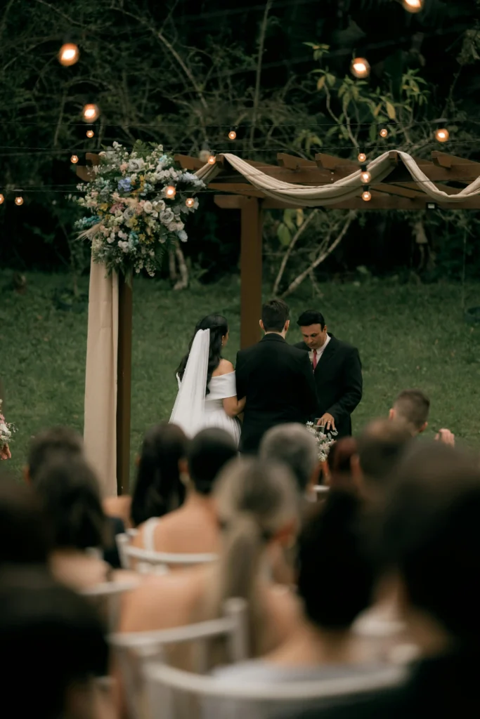 Outdoor garden wedding ceremony with a pastor announcing marriage while guests watch
