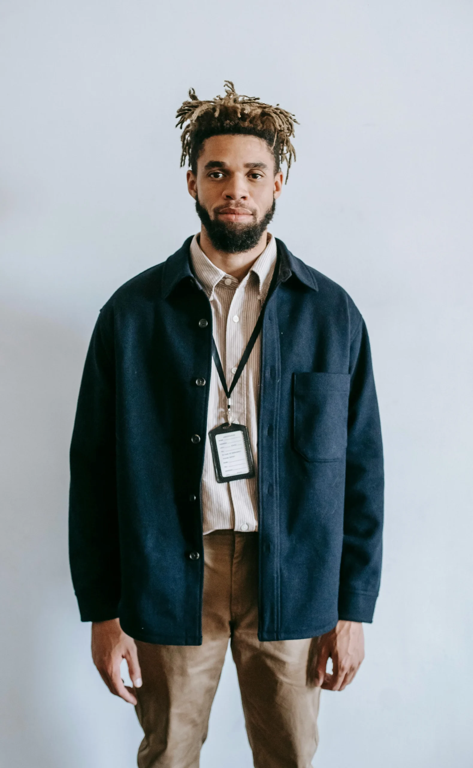 Man standing in a photo studio while taking an ID photo against a plain background.