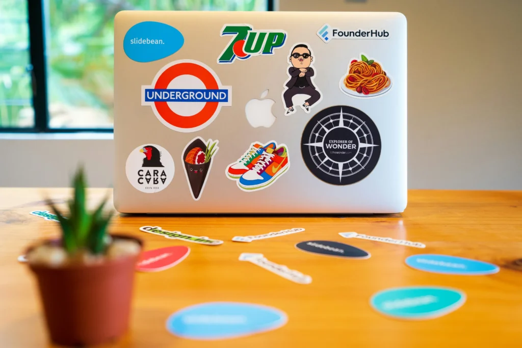 Custom printed stickers attached to the back of a computer and desk surface showcasing vinyl sticker printing services.